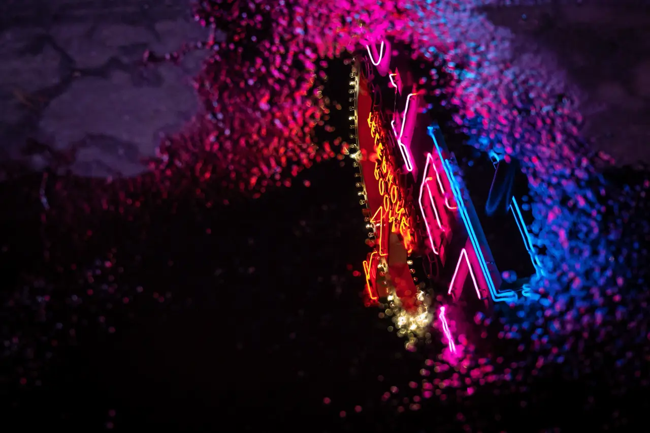 Neon reflected in a rain puddle on worn VHS tape — Original